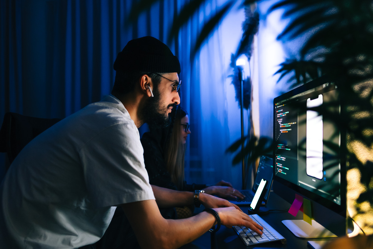 The team of mobile developers writes the program code on a computer
