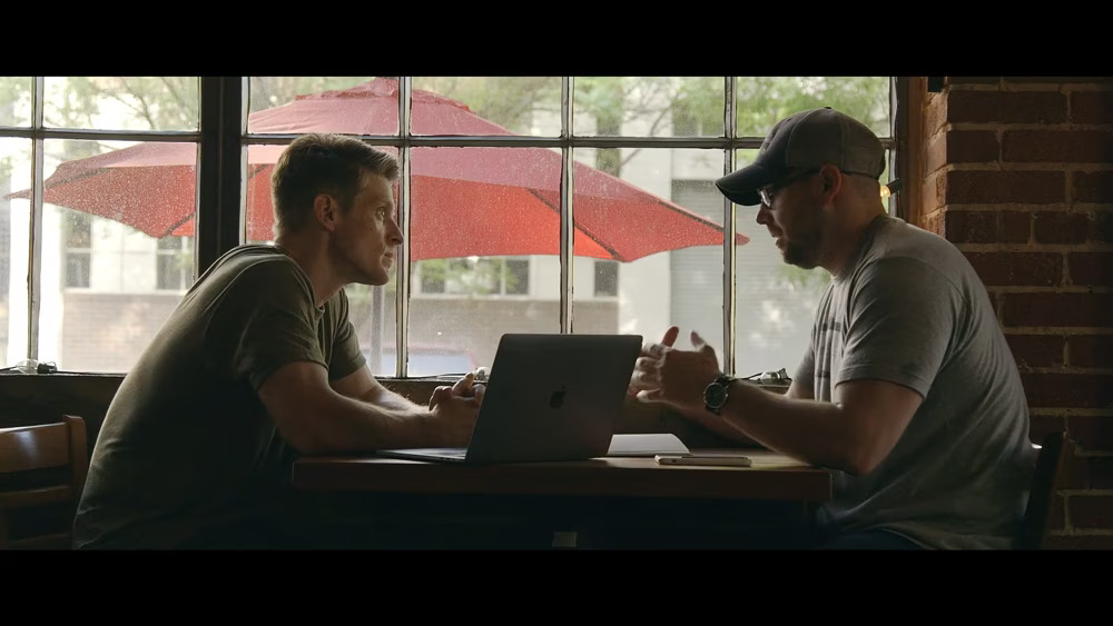 person talking to another person face-to-face at a table