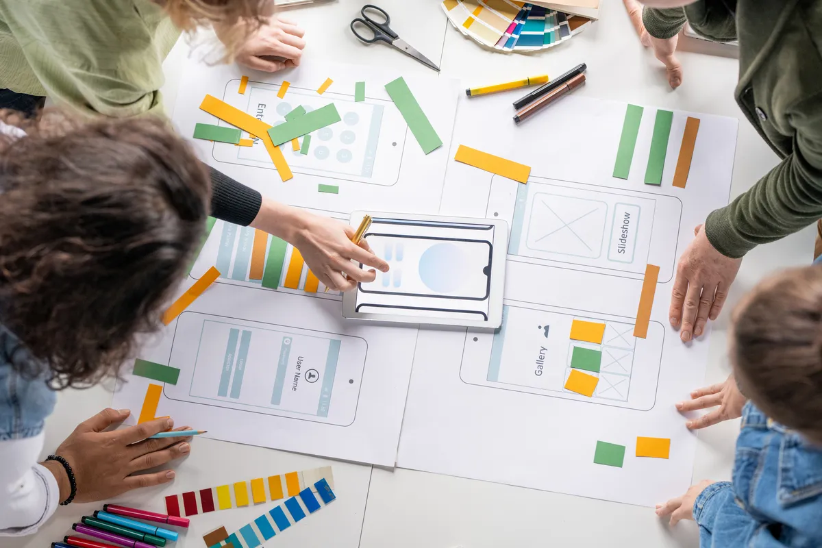 Young creative professional software developers discussing sketches and outlines of new mobile applications at a work meeting