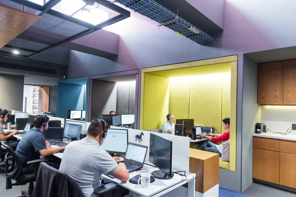 group of people working in a room with computers