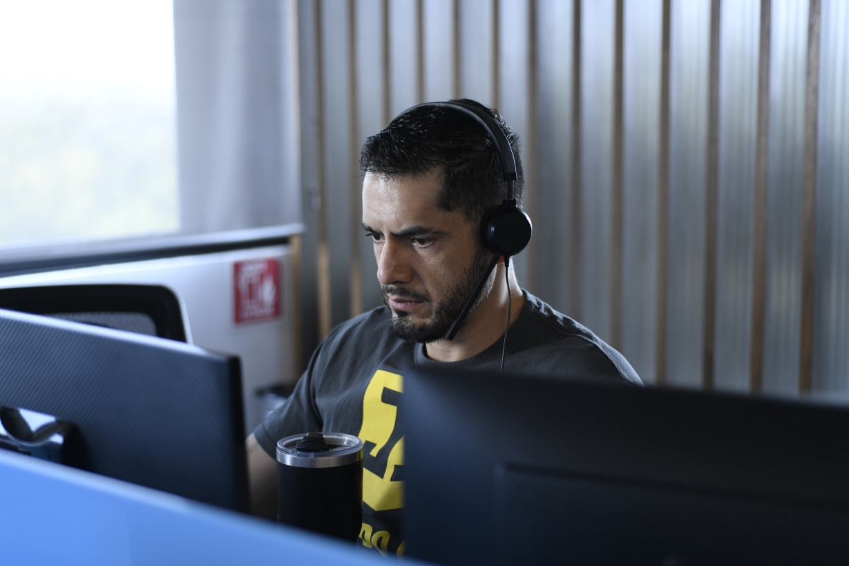 A Unosquare software engineer with headphones on, focusing intently on his computer screen.