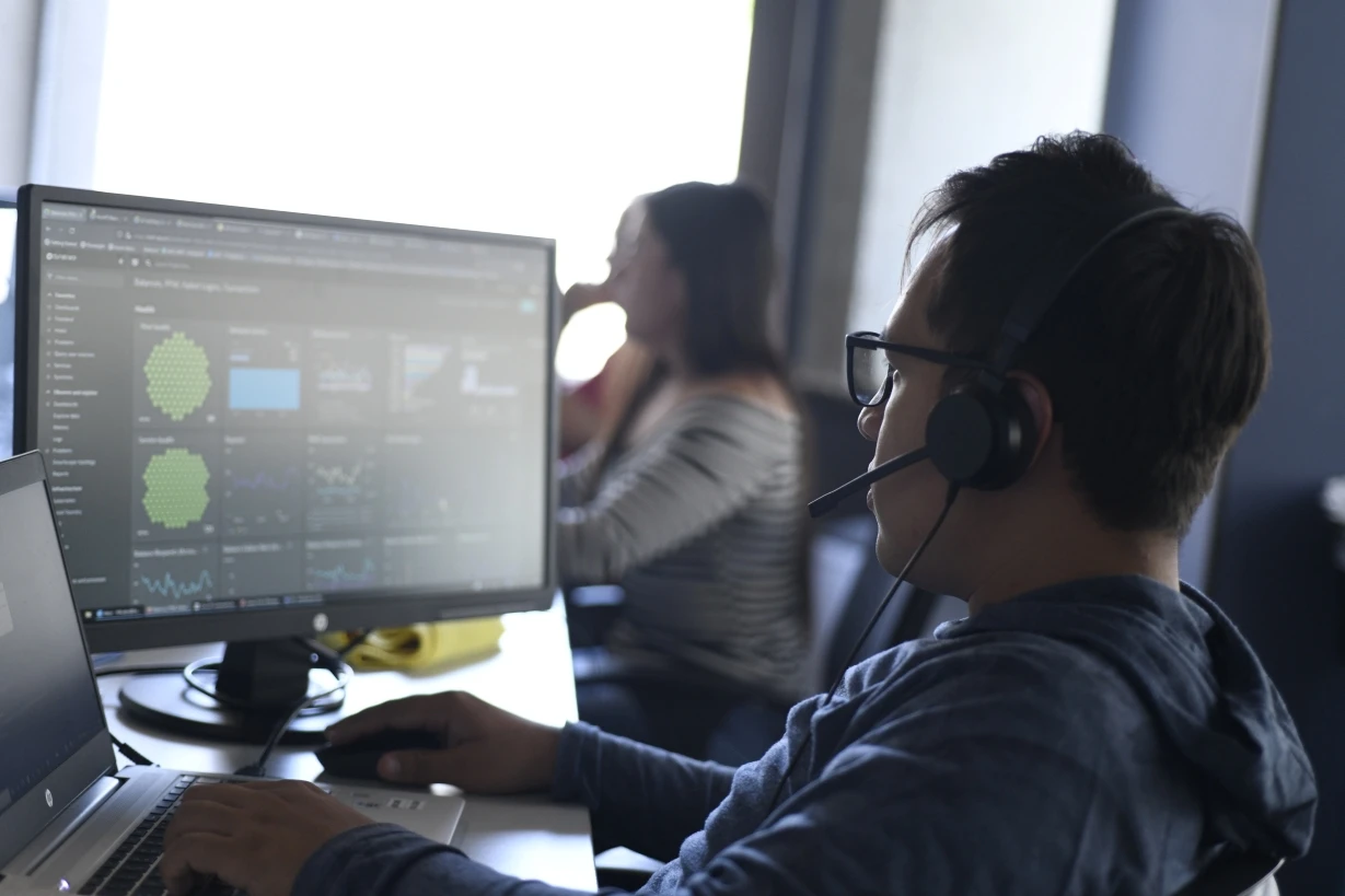 A data analyst at unosquare monitoring system performance on a dashboard in the office.