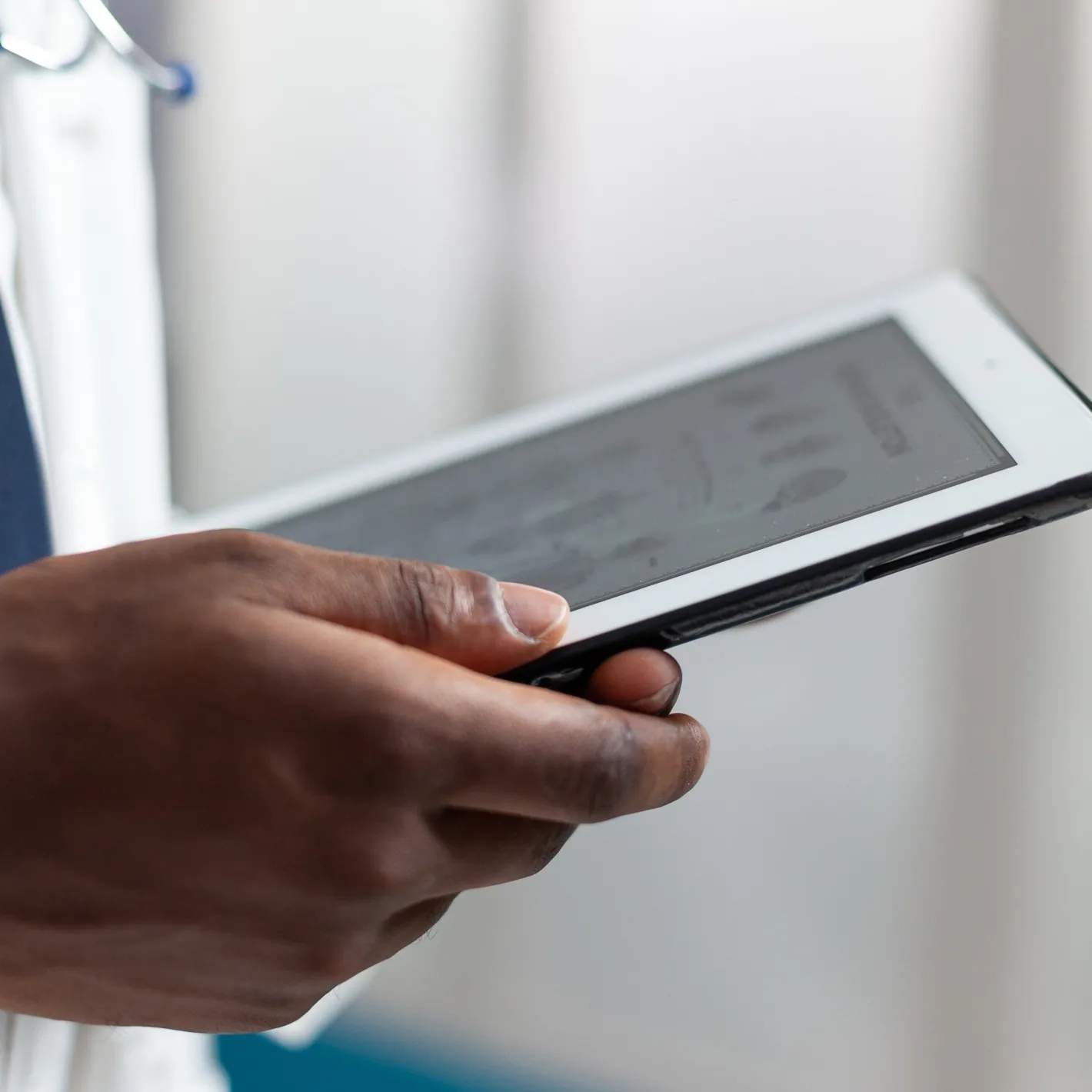 Close-up of a doctor or wellness coach's hand holding a tablet, reviewing patient health data on the Mayo Clinic wellness app dashboard.