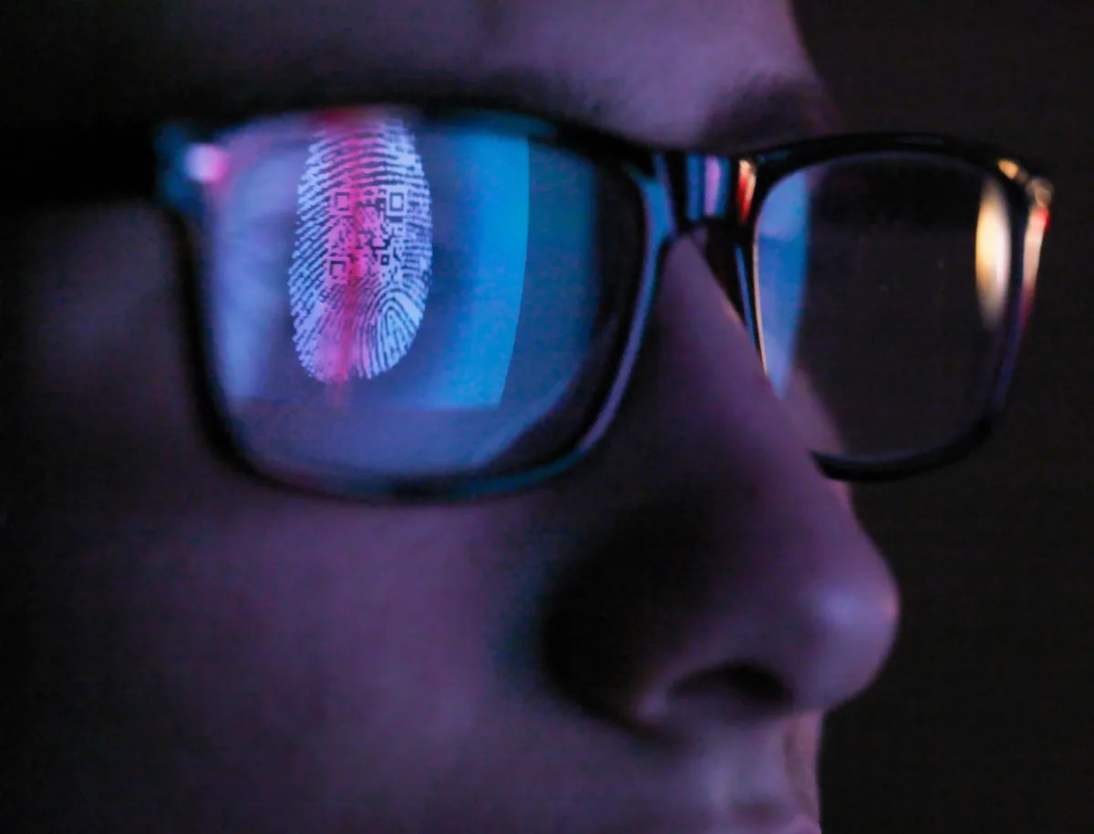 Digital fingerprint with embedded QR code reflected in eyeglasses, symbolizing biometric identity verification technology