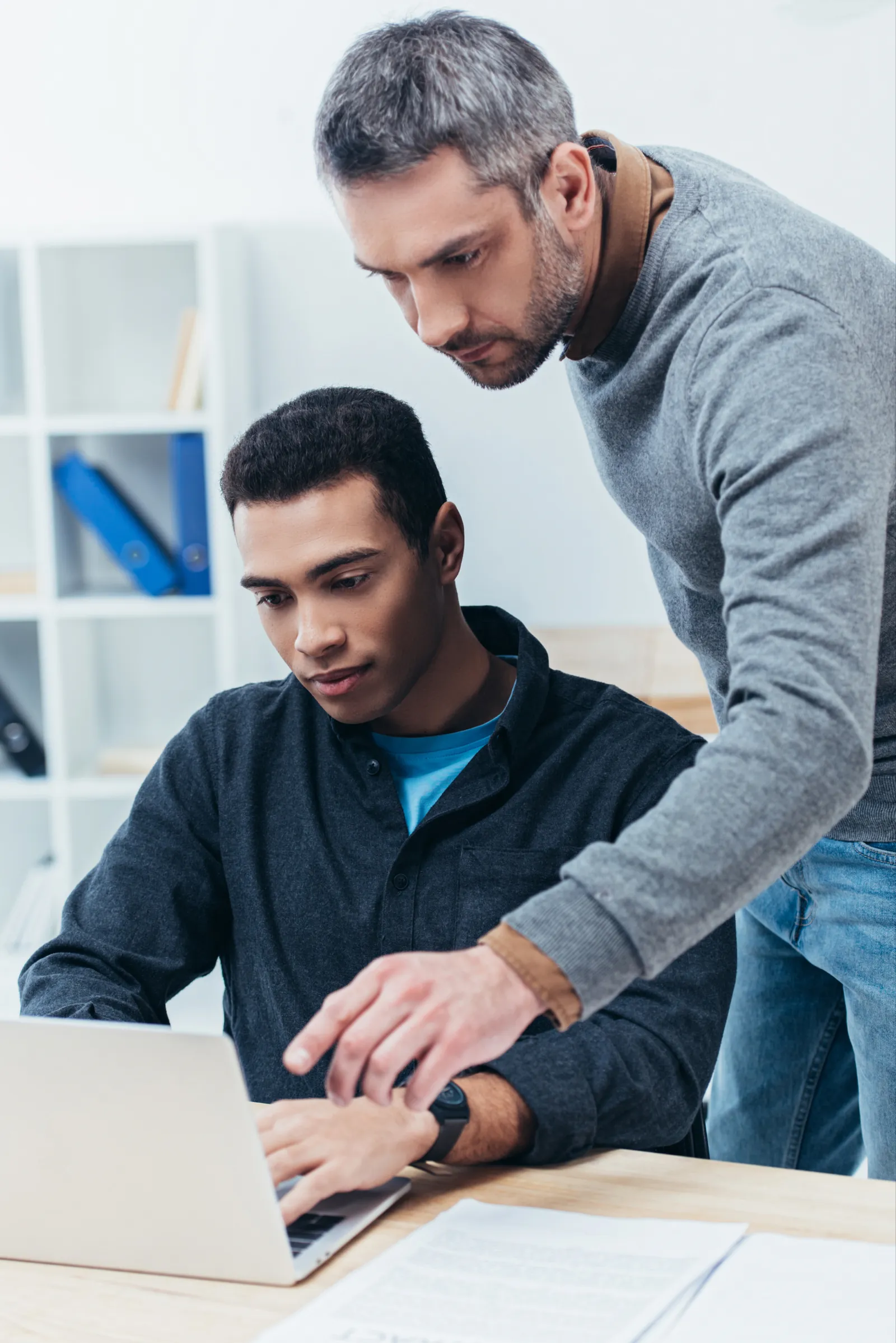 A team lead guiding an engineer at his laptop